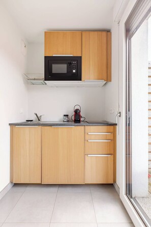 A modern kitchen with wooden cabinets, a built-in microwave, a kettle, and a window. - Sublime Studio, 2 terrasses + vue sur le vignoble (Rosheim)