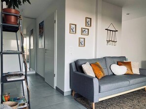 A modern living room with a grey sofa, a plant on a shelf, and framed artwork on the wall. - Sublime Studio, 2 terrasses + vue sur le vignoble (Rosheim)
