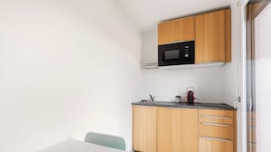 A compact kitchen with a microwave, wooden cabinets, and a small countertop. - Sublime Studio, 2 terrasses + vue sur le vignoble (Rosheim)