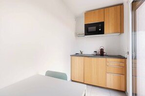 Eine kleine Küche mit einer Mikrowelle, Holzschränken und einer Arbeitsplatte.