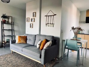 A modern living room with a grey sofa, a dining table with chairs, a wall-mounted decoration, and a bookshelf. - Sublime Studio, 2 terrasses + vue sur le vignoble (Rosheim)
