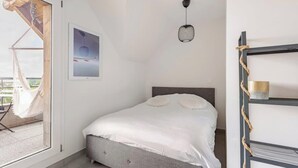 A bedroom with a bed, a hanging light fixture, a framed picture, and a window with a view of the outdoors. - Sublime Studio, 2 terrasses + vue sur le vignoble (Rosheim)