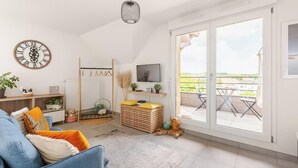 A living room with a sofa, television, and a view of the outdoors through a sliding glass door. - Sublime Studio, 2 terrasses + vue sur le vignoble (Rosheim)