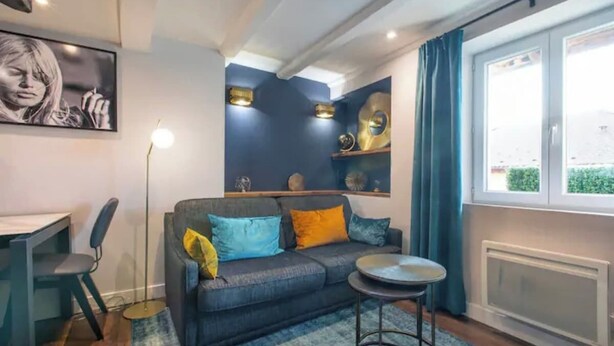 A cozy living area with a sofa, a small round table, a floor lamp, and a window with curtains.