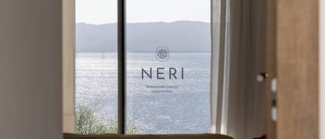 A room with a large window overlooking a body of water and distant mountains.