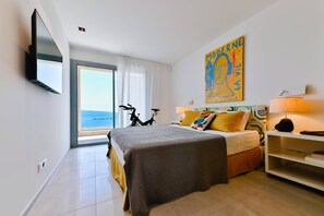 Una habitación de hotel con una cama, una bicicleta, un cuadro y vistas al mar.