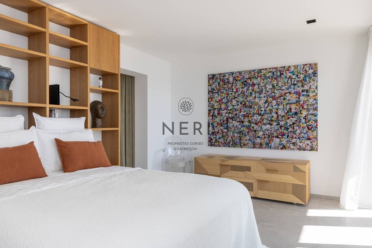 A modern bedroom with a large bed, wooden shelving, a colorful abstract painting, and a minimalist console table.