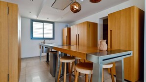 Eine moderne Küche mit einem Holztisch, Barhocker und einem Fenster mit Jalousien.