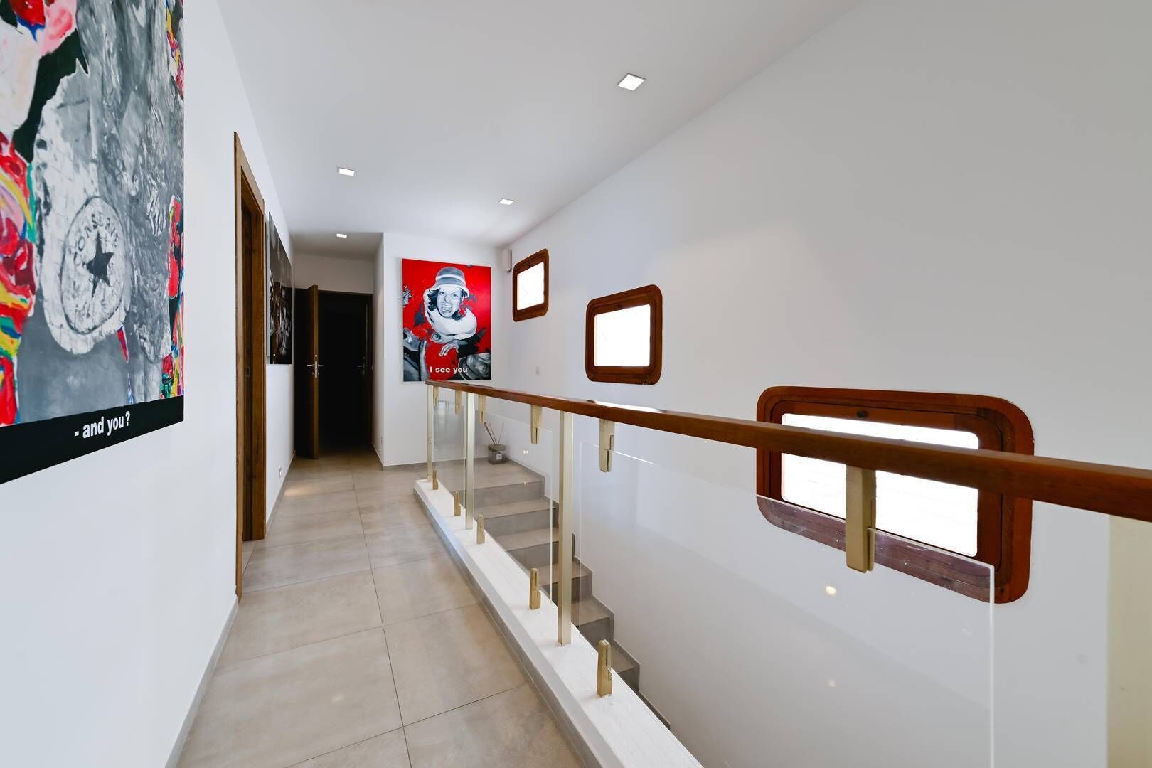 Un interior moderno con una escalera, una pared decorada con obras de arte y una puerta que da a otra habitación.