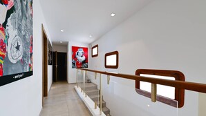 Ein modernes Interieur mit Treppe, einer Wand mit Kunstwerken und einer Tür zu einem anderen Raum.