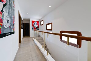 Un interior moderno con una escalera, una pared decorada con obras de arte y una puerta que da a otra habitación.