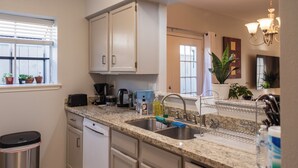 A modern kitchen with granite countertops, stainless steel appliances, and a built-in dishwasher. - Cute Condo with Pool View and lots of charm! (Houston)