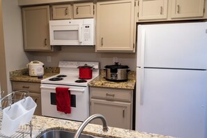 A kitchen with a stove, microwave, and refrigerator. - Cute Condo with Pool View and lots of charm! (Houston)