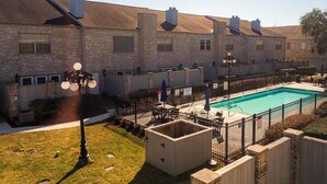 A residential building with a swimming pool, brick exterior, and a fenced patio area. - Cute Condo with Pool View and lots of charm! (Houston)
