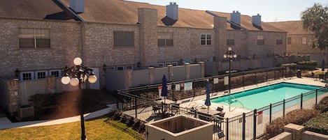 A residential building with a swimming pool, brick exterior, and a fenced patio area.