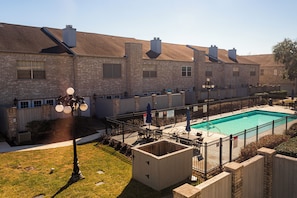 A residential building with a swimming pool, brick exterior, and a fenced patio area. - Cute Condo with Pool View and lots of charm! (Houston)