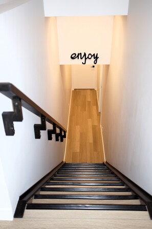 A staircase with a wooden floor and black railings, leading to a landing with a sign that says 'enjoy'. - Private Luxury Retreat - King Bed - Full Kitchen (Calgary)