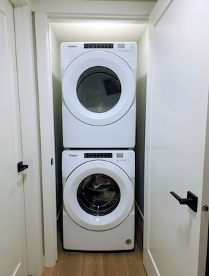 A compact laundry room with two stacked Whirlpool washing machines.
