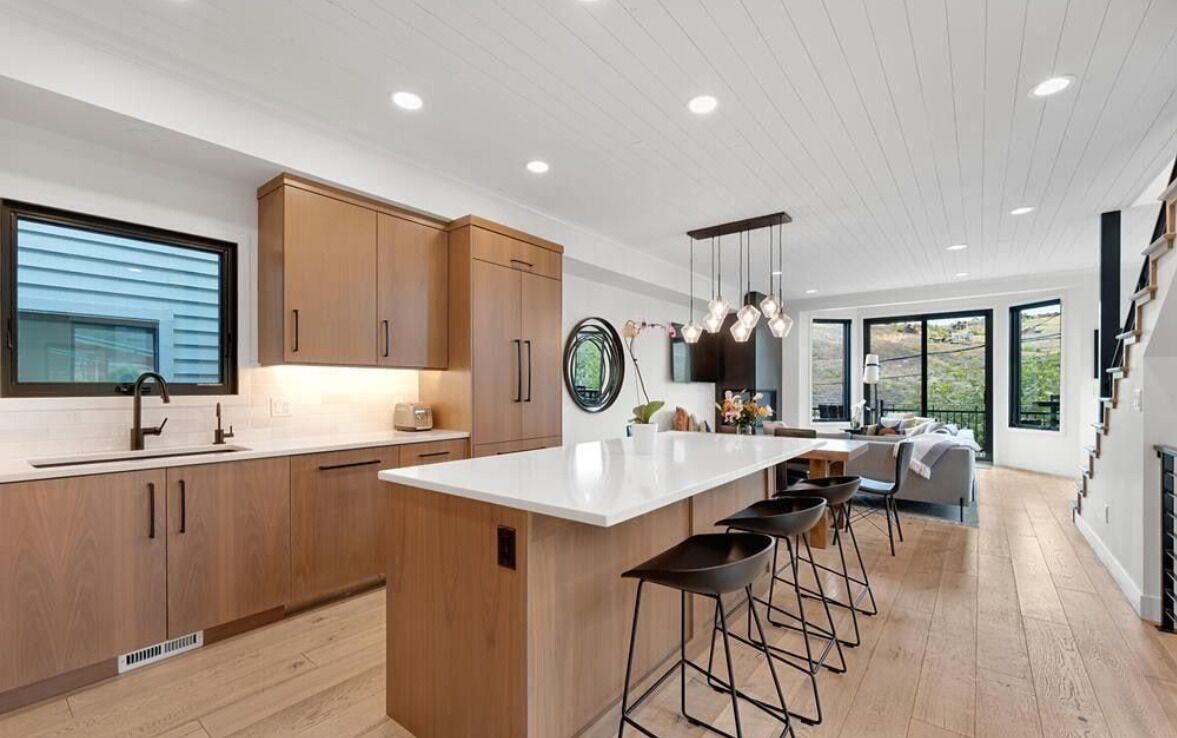Een moderne keuken met houten kasten, een wit aanrecht en een centraal eiland met barkrukken.