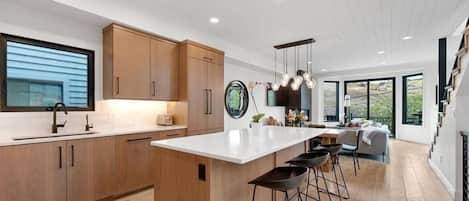 A modern kitchen with wooden cabinets, a white countertop, and a central island with bar stools.