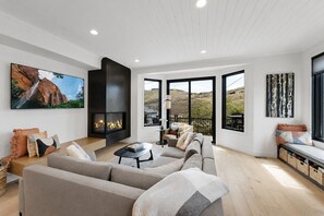 A modern living room with a fireplace, large windows, and a view of the outdoors. - New! Renovated Old Town 4-BD Luxury Home - Short Walk to Slopes and Main Street. (Park City)