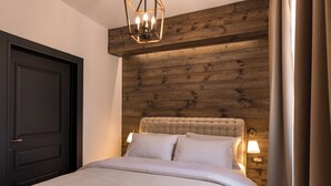 Un dormitorio con una puerta oscura, un cabecero de madera, una cama con ropa blanca y dos lámparas de noche.