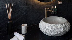 Un baño moderno con un espejo redondo, un lavabo de piedra y una ducha.