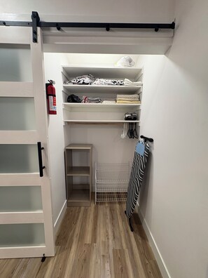 A compact storage area with shelves, a metal rack, and a fire extinguisher. - Beautiful Guesthouse in Kierland. Studio A (Scottsdale)