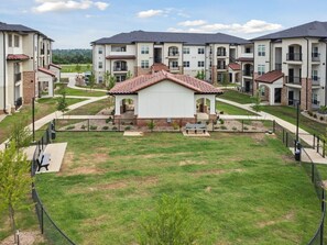 A residential complex with multiple apartment buildings, a central courtyard, and a fenced playground area.