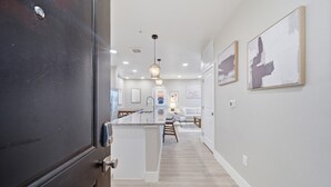 A modern kitchen with a central island, pendant lighting, and a view into a dining area. - Modern 2-Bed/2-Bath Apartment in Owasso, OK (Owasso)