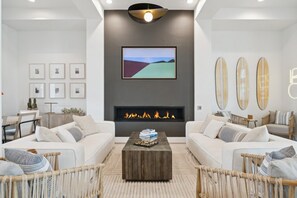 A modern living room with a fireplace, two sofas, a coffee table, and framed artwork on the walls.