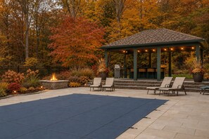 A gazebo with outdoor seating, surrounded by a fire pit and a pool area. - Upscale Fall Retreat | 3 Min URI + Outdoor Oasis (South Kingstown)