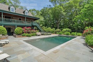 A residential property with a swimming pool, stone patio, and a covered porch with a staircase. - Upscale Fall Retreat | 3 Min URI + Outdoor Oasis (South Kingstown)