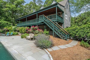 A two-story house with a covered porch, a pool, and a well-maintained garden. - Upscale Fall Retreat | 3 Min URI + Outdoor Oasis (South Kingstown)