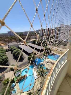 A view of a swimming pool area with a netted balcony. - Thermas Place  (Caldas Novas)