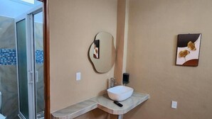 Ein Badezimmer mit Waschbecken, Spiegel und Duschbereich.