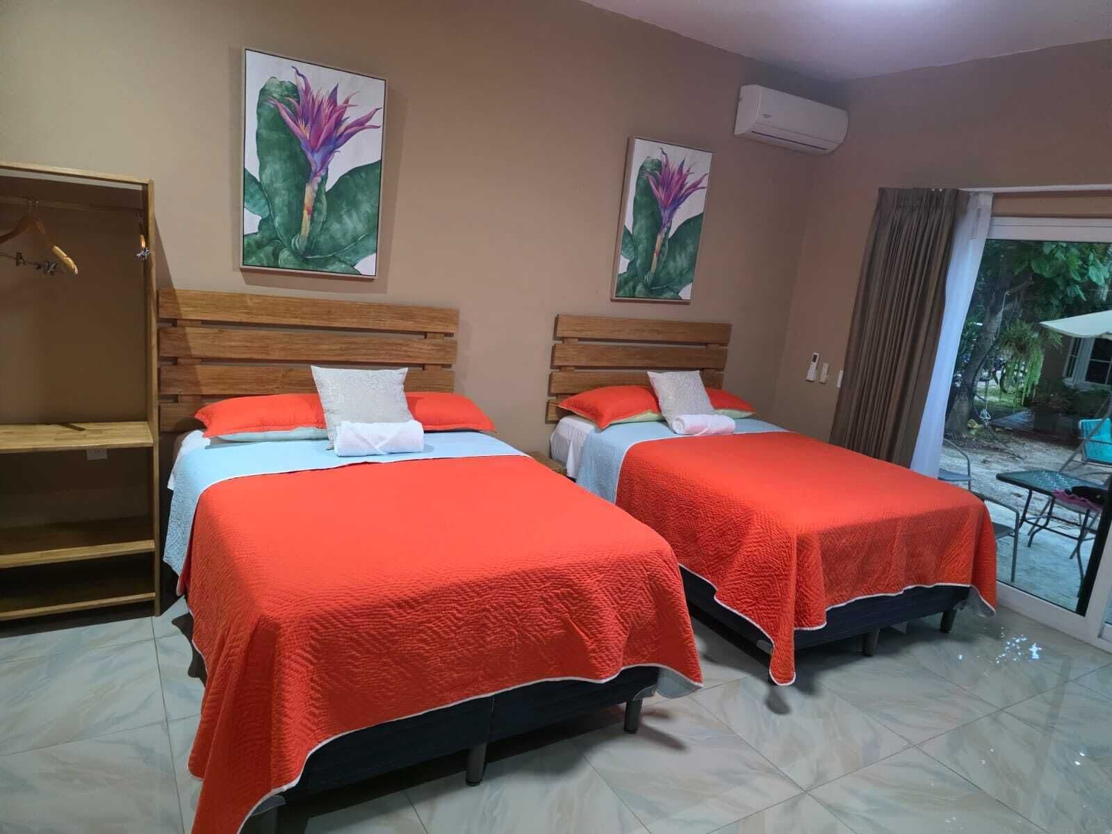 Habitación de hotel con dos camas, un armario y una puerta corrediza de vidrio a un balcón.