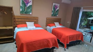 Habitación de hotel con dos camas, un armario y una puerta corrediza de vidrio a un balcón.