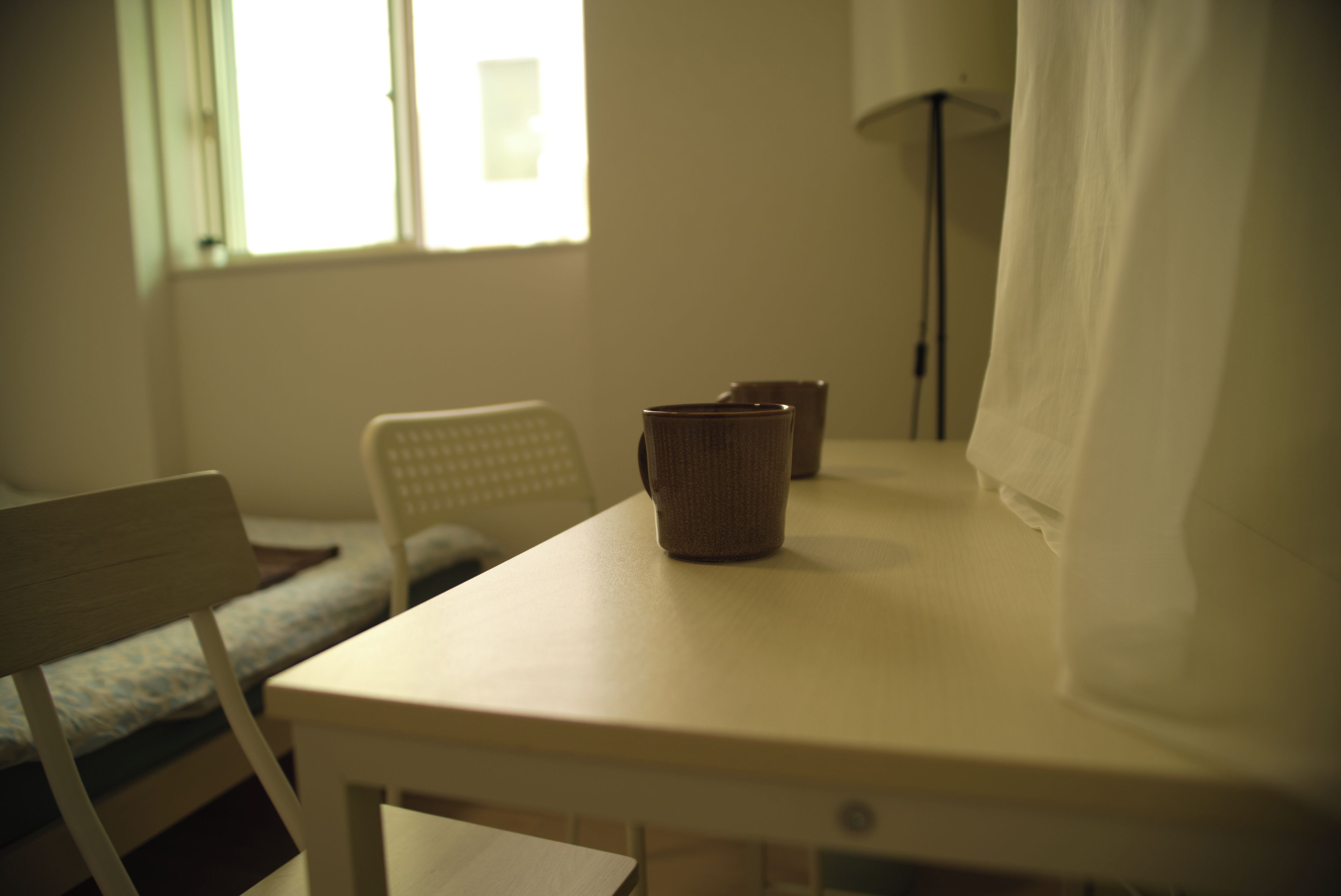 A room with a bed, a chair, a table, and a lamp.