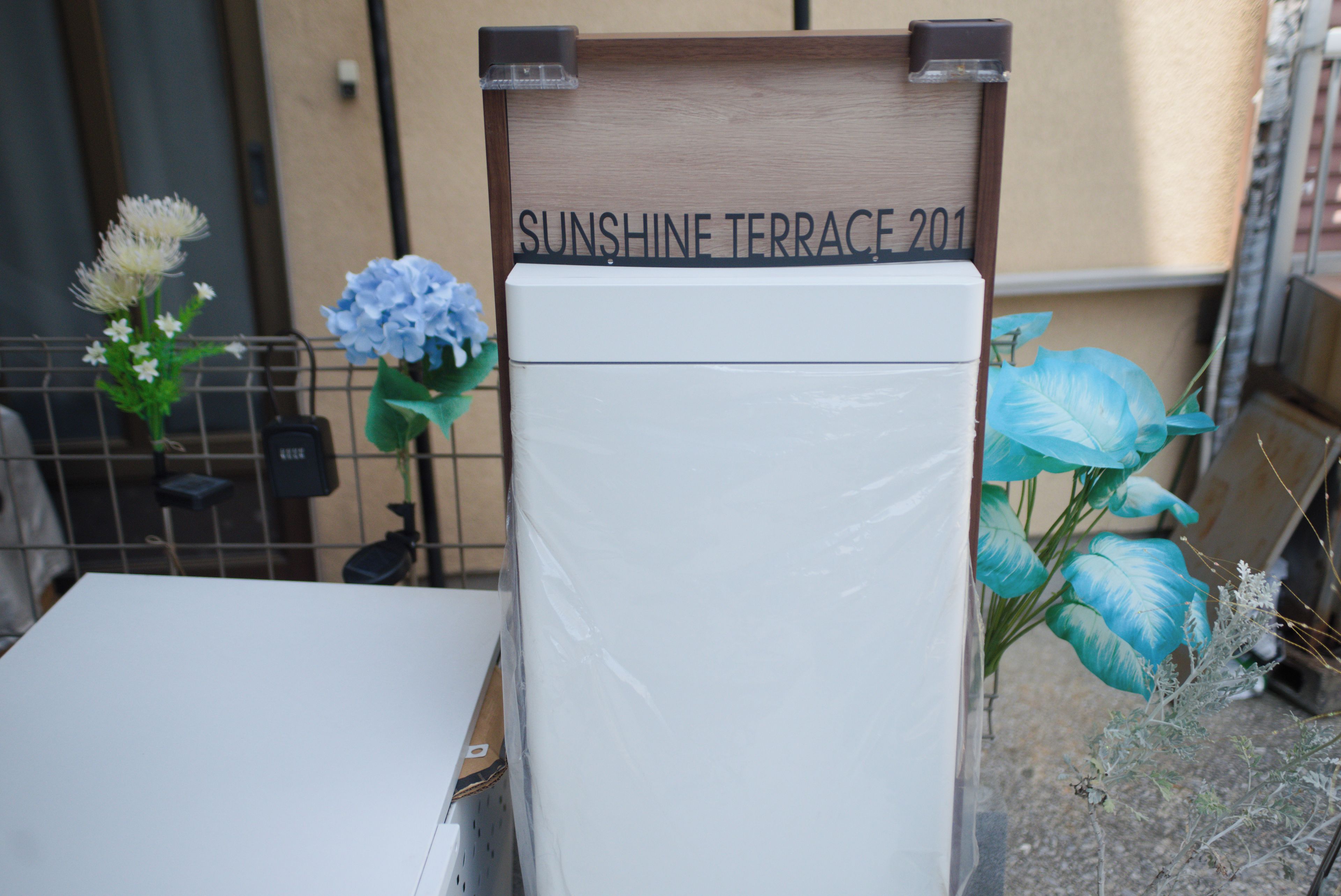Un réfrigérateur blanc, avec une pancarte au-dessus indiquant « SUNSHINE TERRACE 201 ».