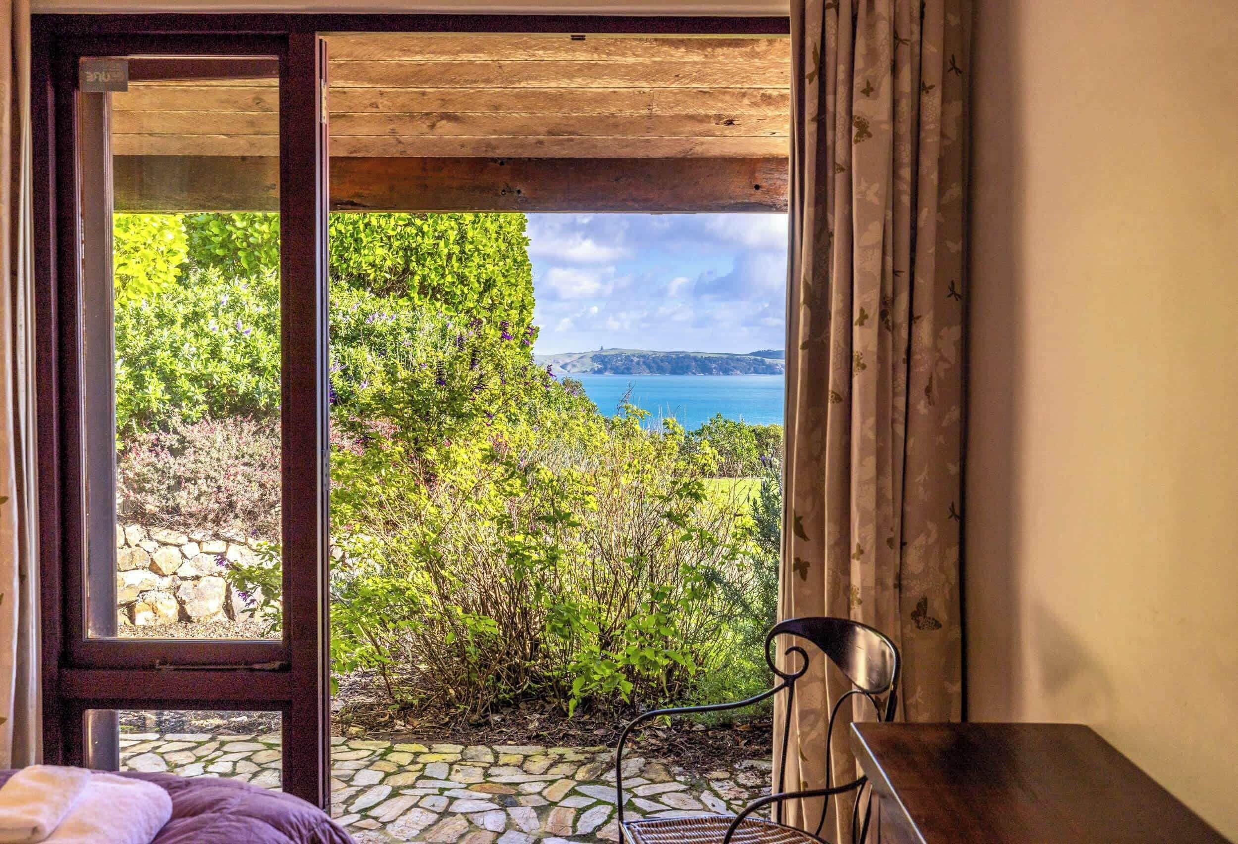 A room with a view of a garden and a body of water.