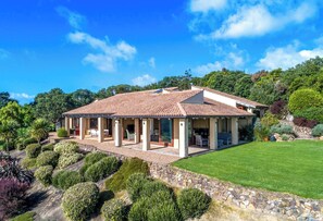 Une maison avec un toit en tuiles, un patio couvert et un jardin bien entretenu.