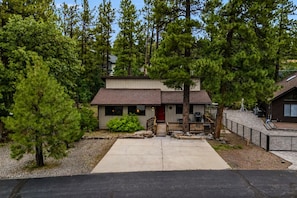 A two-story building with a front porch, a covered patio, and a driveway.