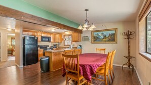 A spacious kitchen with wooden cabinets, a dining area with a table and chairs, and a painting on the wall.