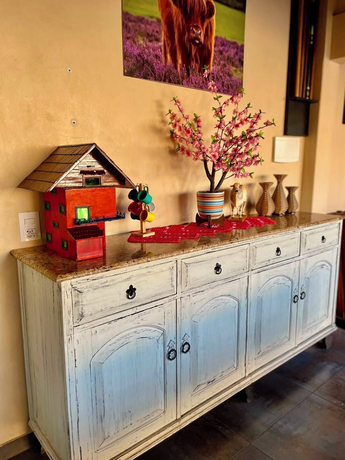 A white cabinet with drawers and a small house model on top.