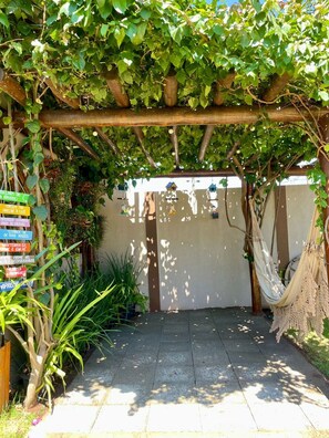 A covered outdoor area with a pergola, hanging bird feeders, and a hammock.