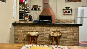 Une cuisine avec un four en briques, des tabourets en bois et des luminaires suspendus.