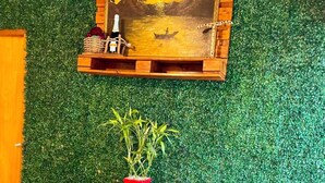 Une pièce avec un mur vert, un meuble en bois, une petite table avec une plante et un tableau au-dessus du meuble.