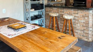 Une cuisine rustique avec un four en briques, des tabourets de bar en bois et un tableau représentant des perroquets.