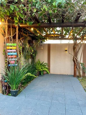 A covered walkway with a signpost listing various services, surrounded by greenery and potted plants.
